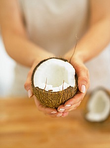 woman's hands holding cut open coconut with lauric acid